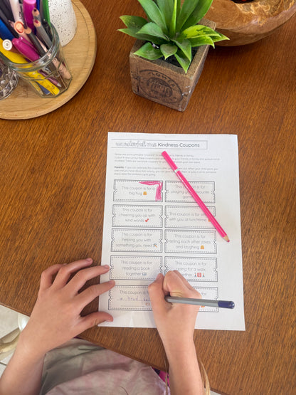 Person filling out a worksheet with a pink pen on a wooden table.